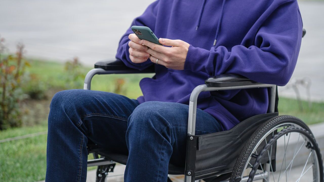 Young man on the phone in the wheelchair on the street