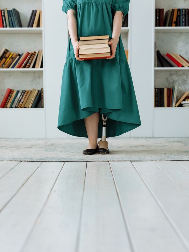 young lady with a prosthetic leg and stock of books