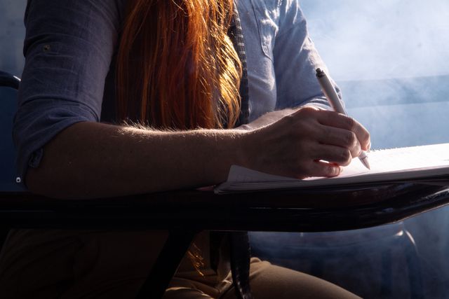 A red head lady sitting and writing by hand